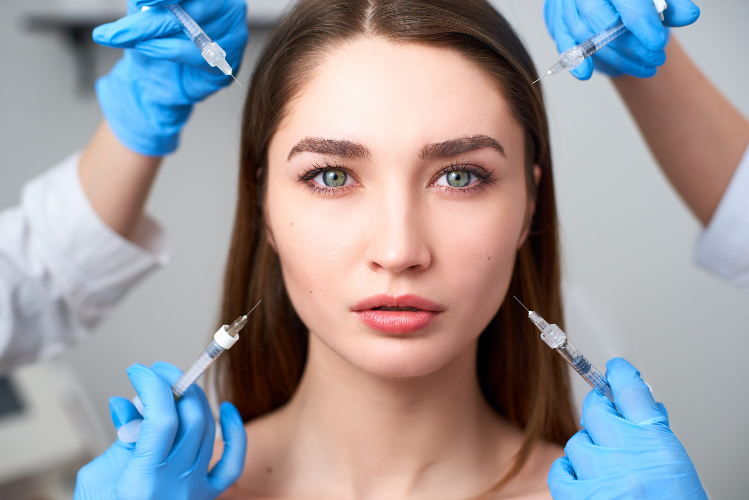Beautiful woman's face with 4 syringes of filler